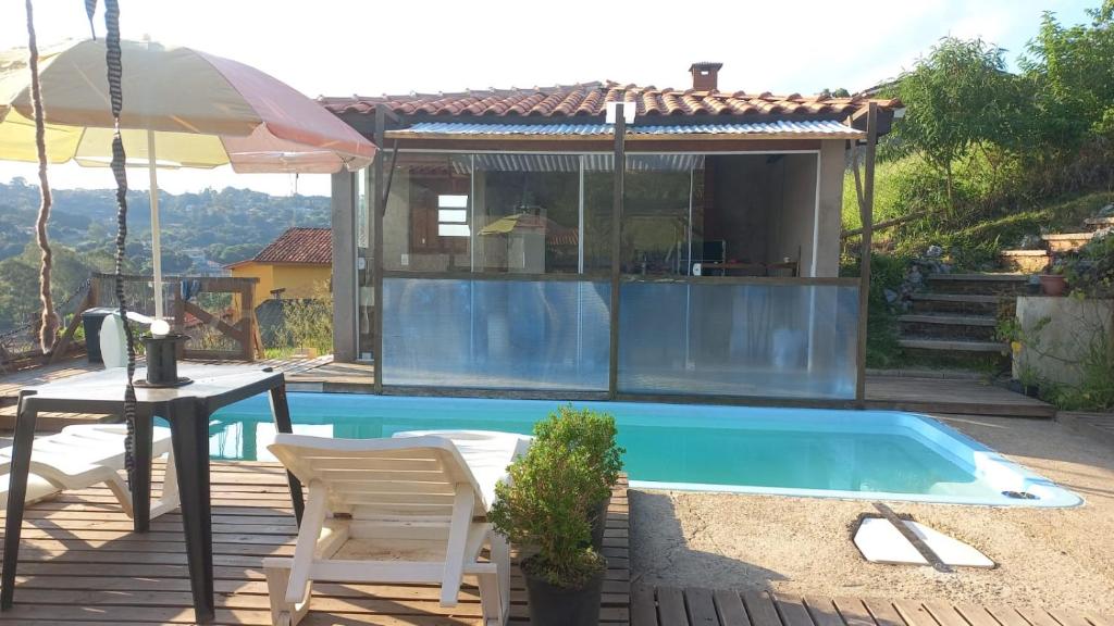 een zwembad met een tafel en een parasol bij Recanto Bella Roma in Itatiba