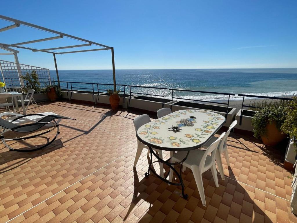 Ein Tisch und Stühle auf einem Balkon mit Meerblick in der Unterkunft The Seaside Serenity Terrace in Giardini-Naxos