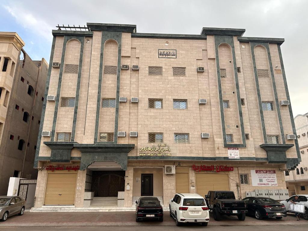 een groot gebouw met auto's ervoor geparkeerd bij شقق مفروشة 22 in Al Madinah