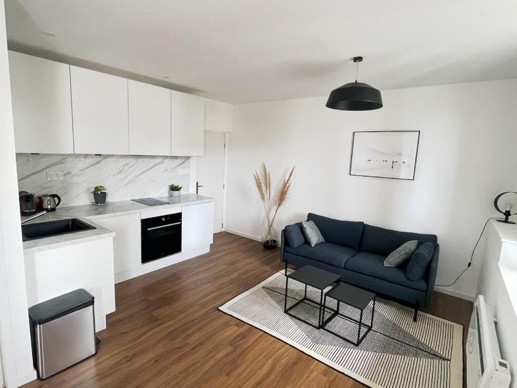 un salon avec un canapé bleu et une cuisine dans l'établissement Hono - Studio en plein coeur du centre ville, à Dax