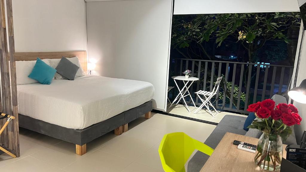 a bedroom with a bed and a table and a balcony at HOTEL 9.5 SAN FERNANDO in Cali