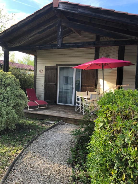 eine Terrasse mit einem roten Regenschirm, einem Tisch und Stühlen in der Unterkunft Chez Marielle in Parentis-en-Born