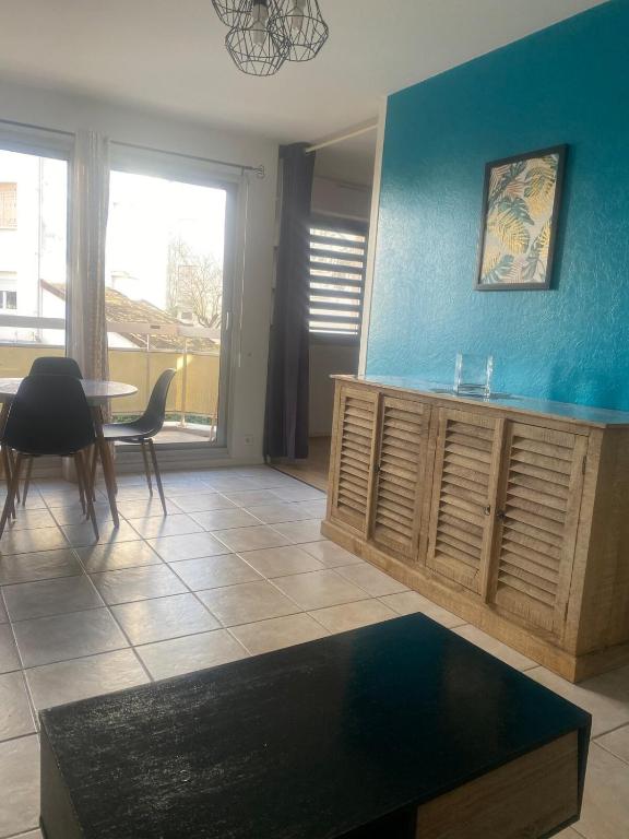 un salon avec une table et un mur bleu dans l'établissement Un F2 Au cœur du centre ville avec parking privé et balcon, à Auxerre