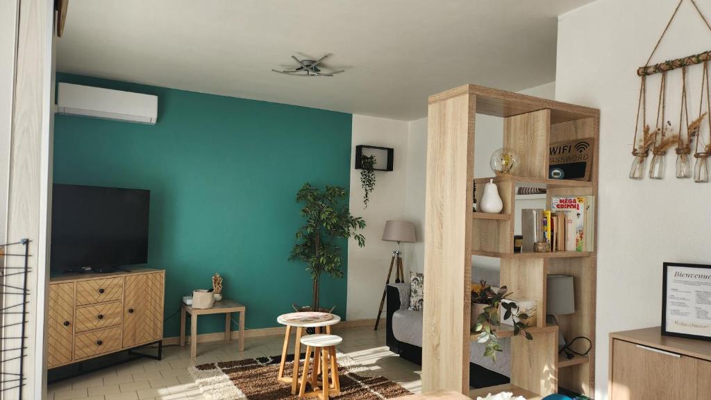Il comprend un salon doté d'une télévision et d'un mur bleu. dans l'établissement Charmant T2 Béziers centre ville avec balcon, à Béziers