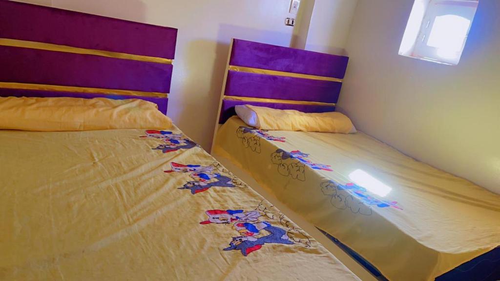 two beds sitting next to each other in a bedroom at tmem home in Jazīrat Aswān