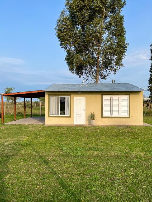 a small yellow house in a yard with a tree at La Leontina in Villa Elisa