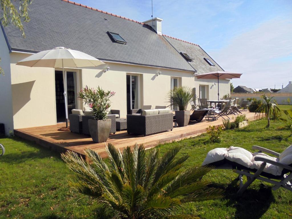 une maison avec une terrasse dotée de chaises et d'un parasol dans l'établissement La Dunette, à Penmarcʼh