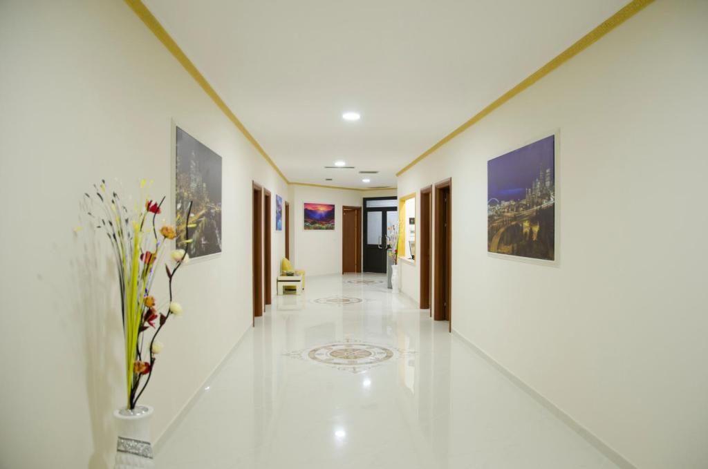 un pasillo con pinturas en las paredes y un jarrón con flores en Ikea Hotel, en Tirana