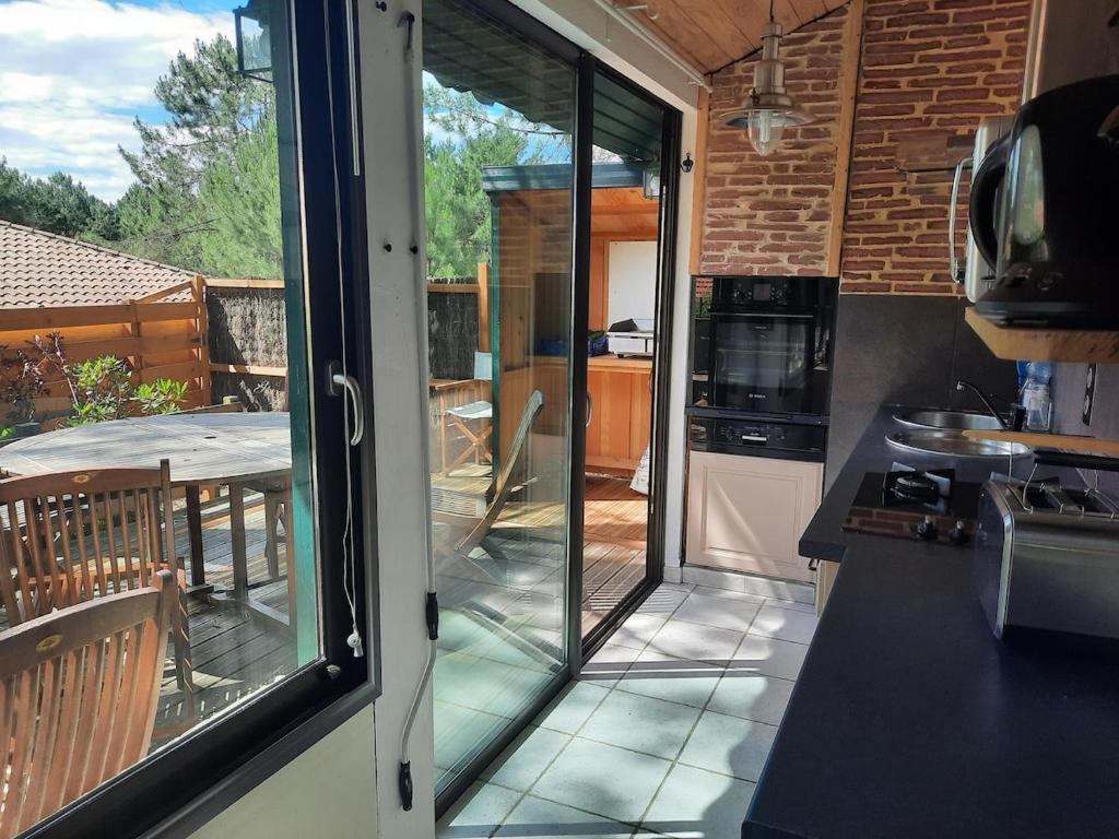 une cuisine avec une porte coulissante en verre menant à une terrasse. dans l'établissement Agréable petite maison près du golf et de la plage, à Moliets-et-Maa