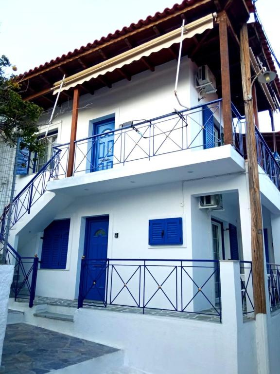 a white house with blue doors and a balcony at Kea's Living Yard II in Korissia