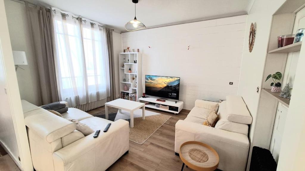 - un salon avec deux canapés blancs et une télévision dans l'établissement Maison Cosy avec Jardin Proche 24h du Mans, au Mans