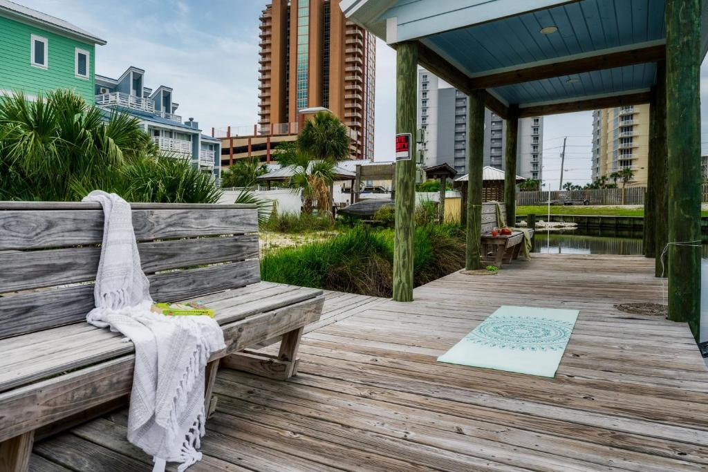 eine Holzbank auf einer Holzterrasse mit einer Matte in der Unterkunft Cozy Girls Summer Getaway! Bungalow w Private Beach! in Gulf Shores