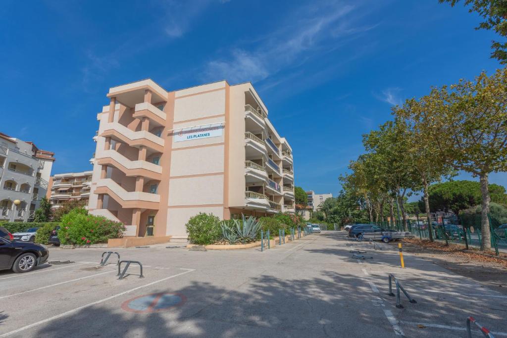 un grand bâtiment dans un parking à côté d'une rue dans l'établissement PARFUM DE MIMOSA, à Sainte-Maxime