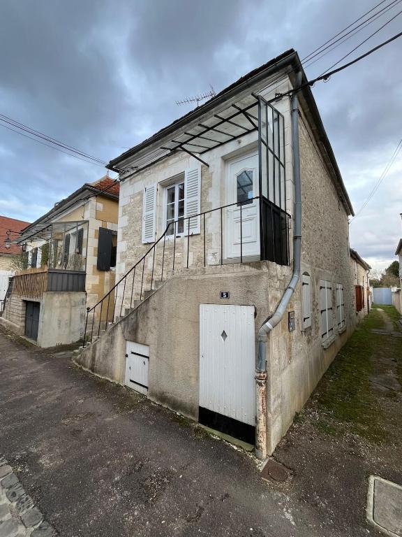 un ancien bâtiment avec un escalier sur son côté dans l'établissement Maison de la Fontaine, à Champs
