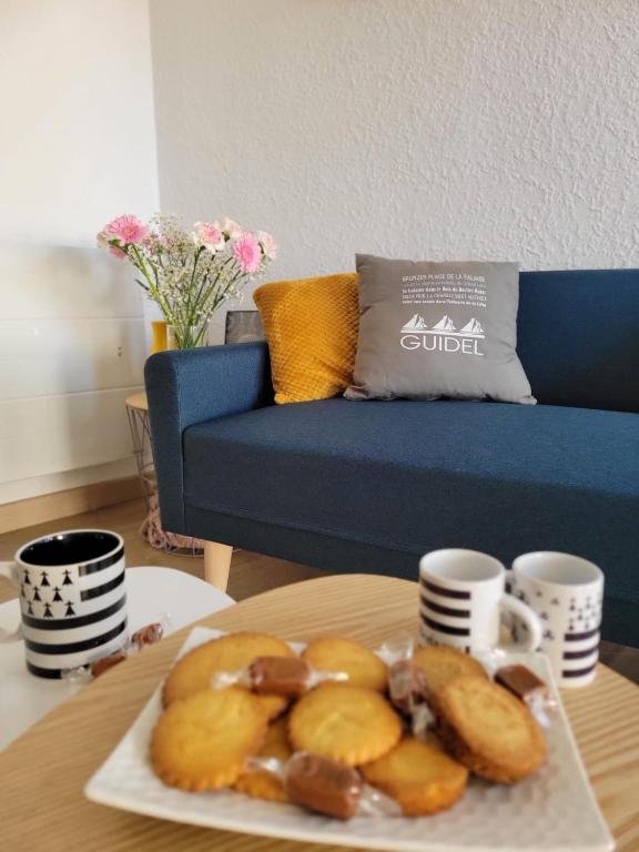 une table avec un plateau de beignets et des tasses à café dans l'établissement Appart cosy avec terrasse et parking privé, à Guidel