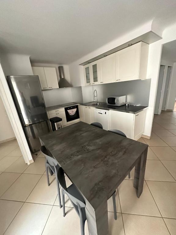 une cuisine avec une table en bois avec des chaises et un réfrigérateur dans l'établissement Juan les pins near beach, à Antibes