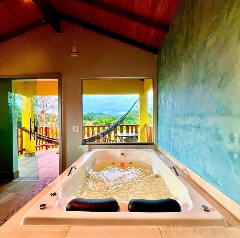 a jacuzzi tub in a room with a balcony at Chalé Verde Bonança in Pirenópolis