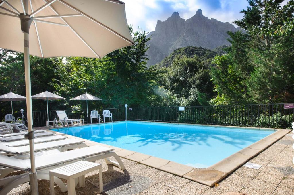 a swimming pool with chairs and an umbrella at Hotel et Résidence Cala di sole in Porto Ota