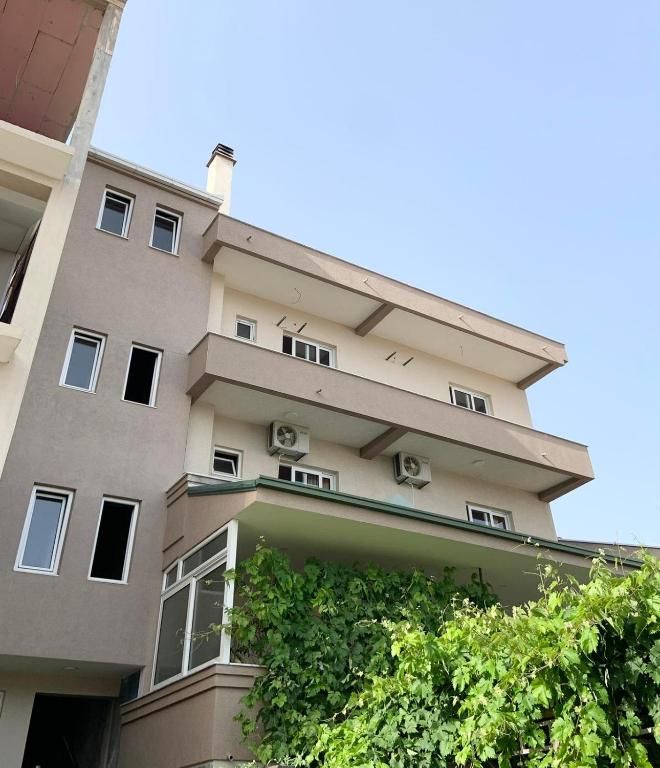 a tall apartment building with a green hedge at Cache Apartments in Ulcinj