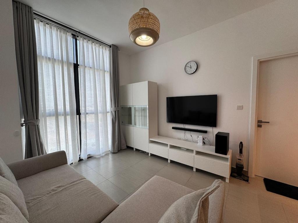 un salon avec un canapé et une télévision à écran plat dans l'établissement Royal Vacation Home - Modern 1BR, à Charjah