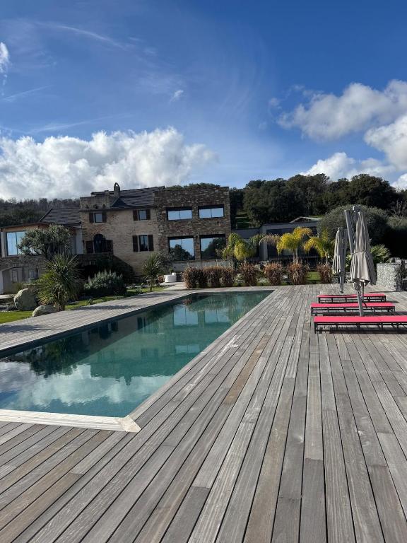 - une piscine avec 2 chaises et des parasols sur une terrasse en bois dans l'établissement Villa avec dépendance vue mer piscine privée 12p, à Penta-di-Casinca