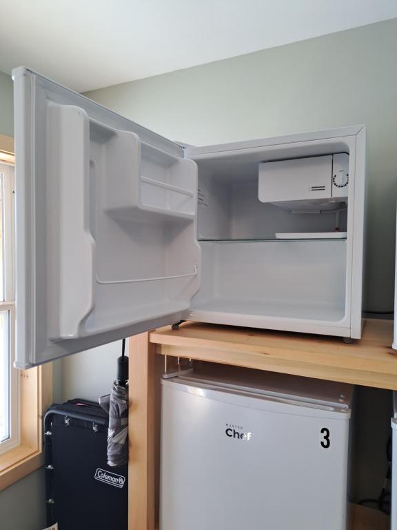 a refrigerator with its door open on a desk at The Zzzz Moose Camping Cabins in Birch Plain