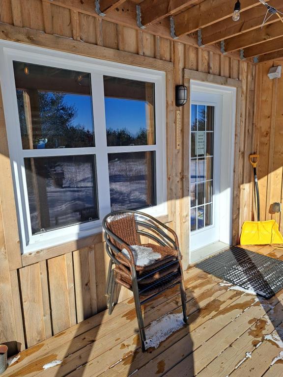 a rocking chair sitting in a room with windows at The Zzzz Moose Camping Cabins in Birch Plain