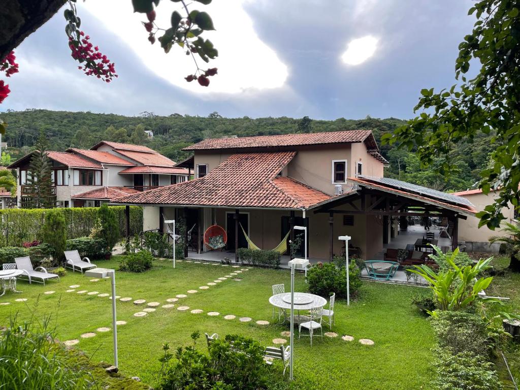 a house with a yard with a table and chairs at Pousada Monteflor Guaramiranga-CE in Guaramiranga