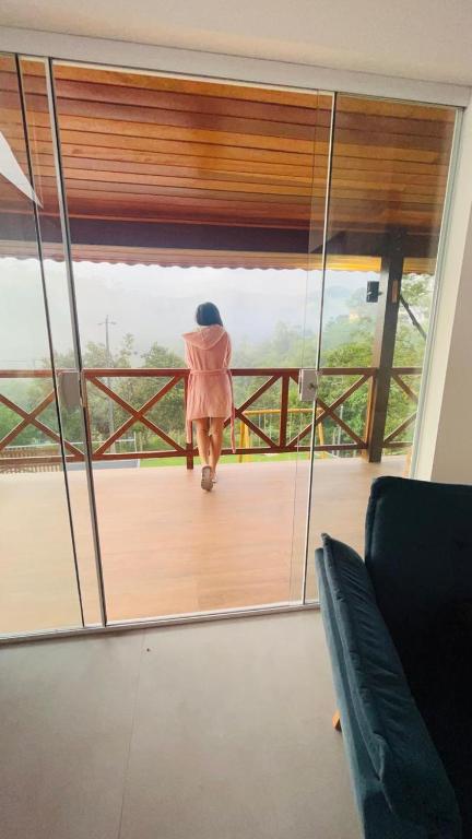 a woman walking on a balcony looking out of a mirror at A Casa do Júnior em Visconde de Mauá in Visconde De Maua