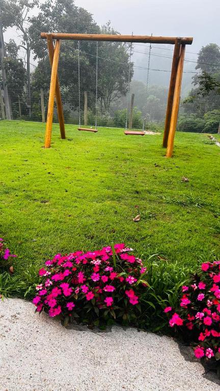 a park with pink flowers in the grass at A Casa do Júnior em Visconde de Mauá in Visconde De Maua