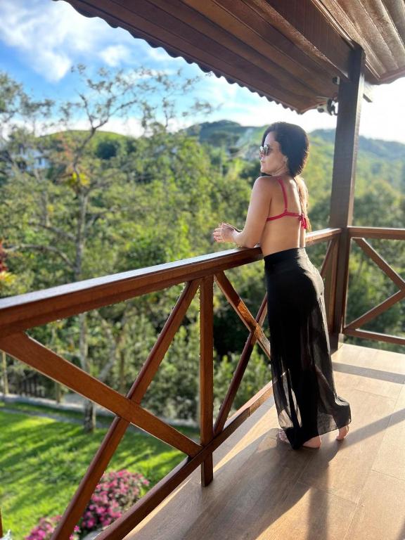 a woman standing on the balcony of a house at A Casa do Júnior em Visconde de Mauá in Visconde De Maua
