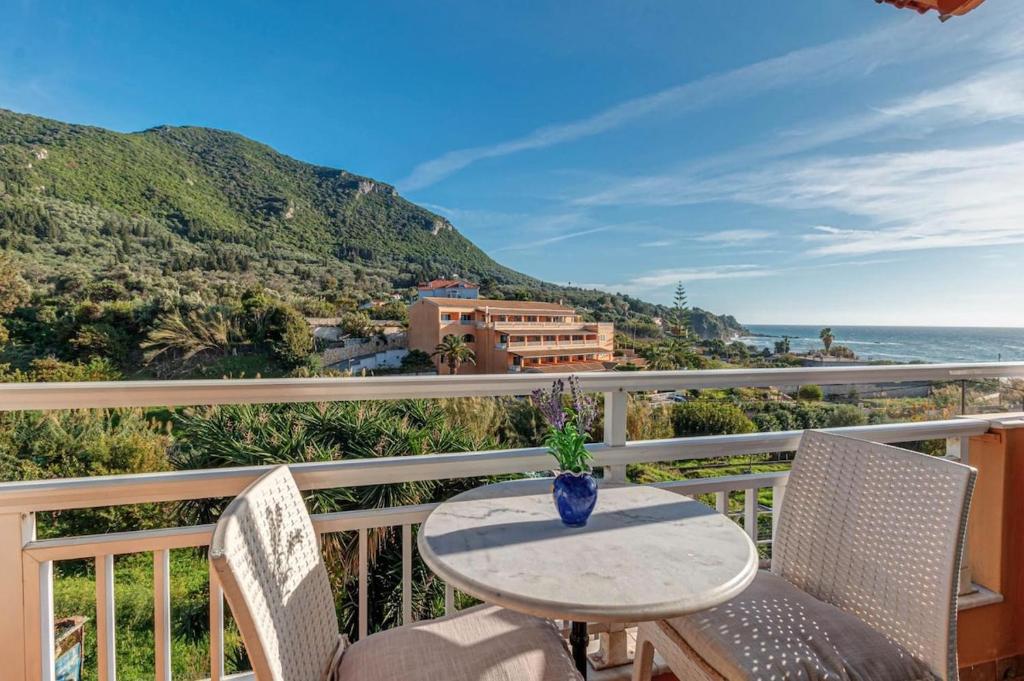a table and chairs on a balcony with the ocean at Charming Studio Just Steps from Paramonas Beach in Paramonas