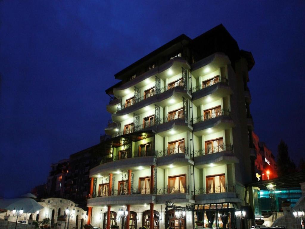 a tall building with lights on it at night at Dinasty Hotel in Tirana