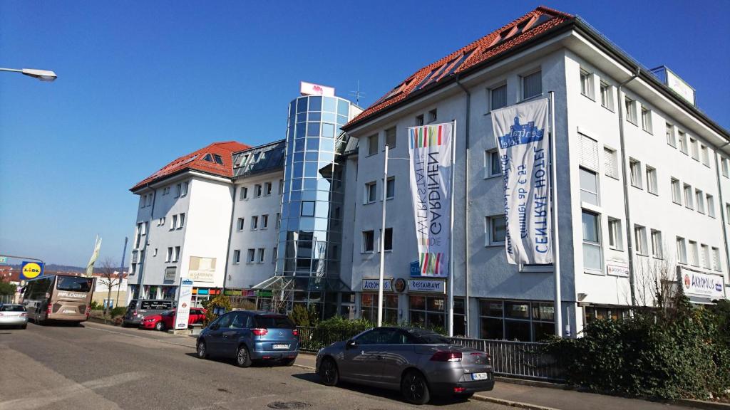 a building with cars parked on the side of a street at Central Hotel Winnenden in Winnenden