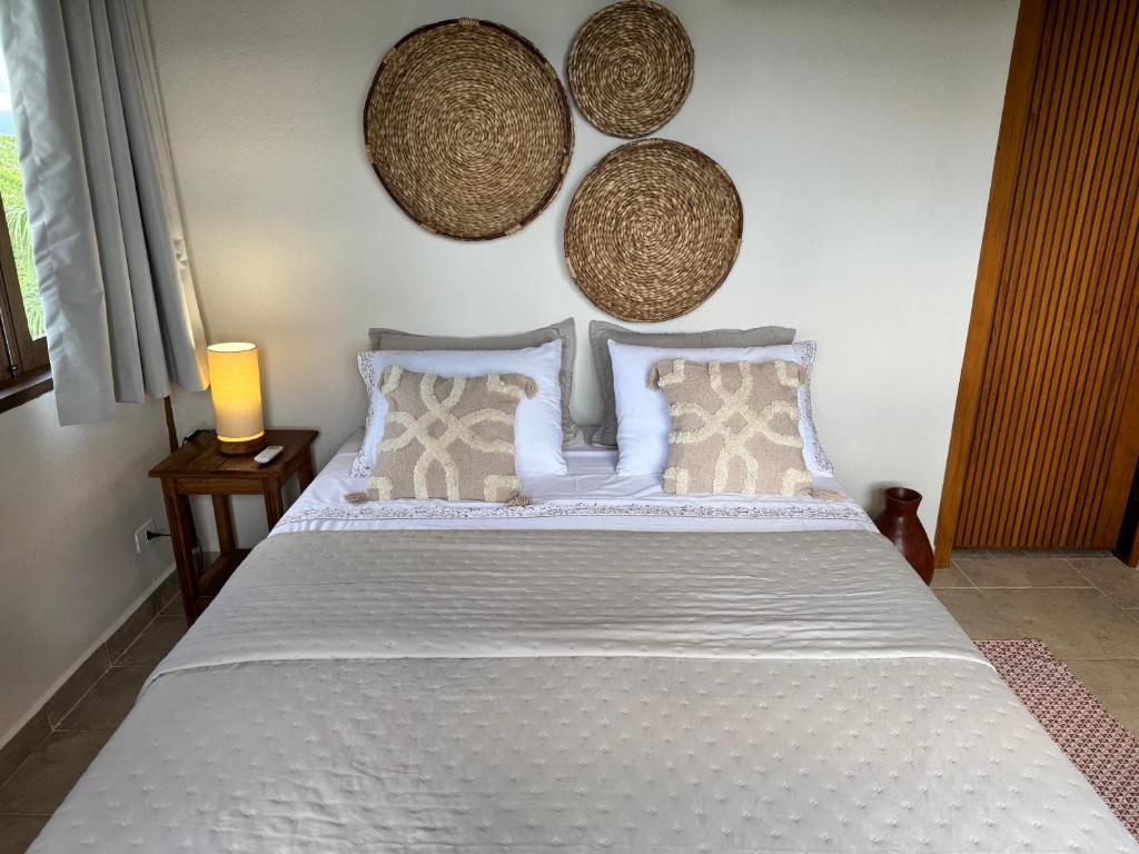 ein Schlafzimmer mit einem weißen Bett mit Kissen und einer Wand in der Unterkunft Suíte Deluxe com vista para Ilhabela in São Sebastião