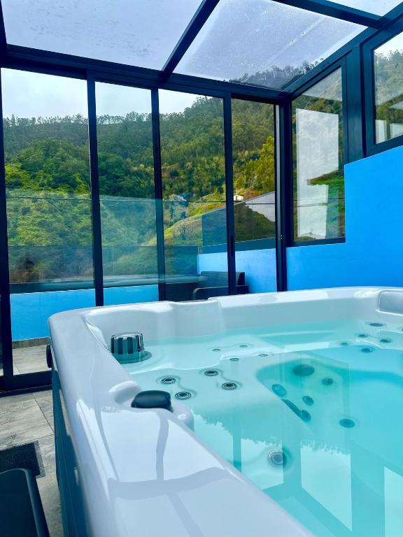 a bath tub in a room with windows at AGUIAR´S VILLAGE in Ribeira Brava