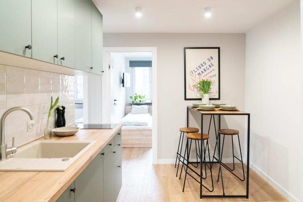 a kitchen with white cabinets and stools at Chmielna Central Apartments in Warsaw