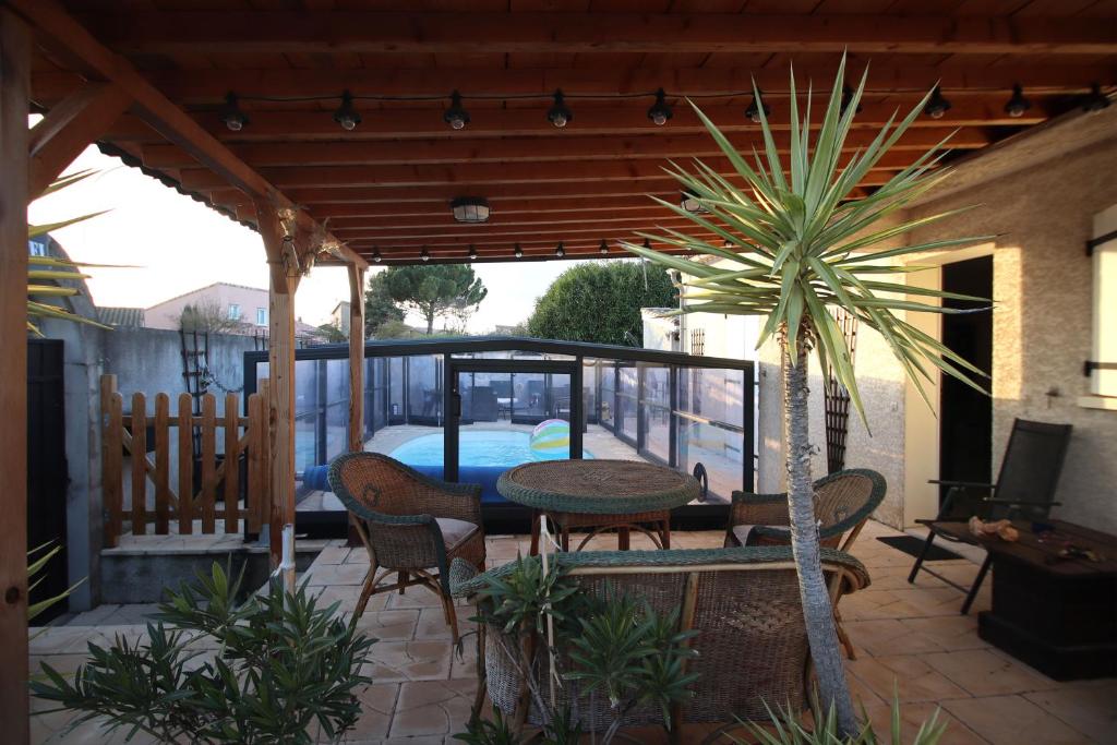 un patio avec une table, des chaises et un palmier dans l'établissement Magnifique villa avec piscine, à Carcassonne
