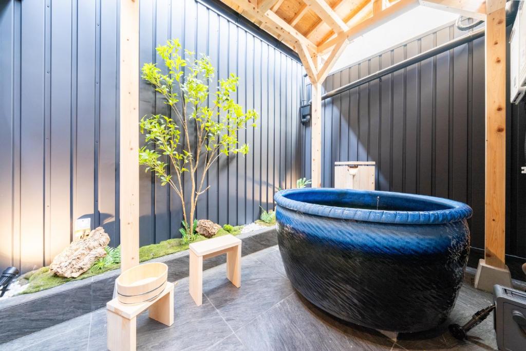 a large blue pot sitting on a patio with a tree at おそば 露天風呂でリラックス ベッド7台 usjへ11分 商店街に位置するお宿 in Osaka