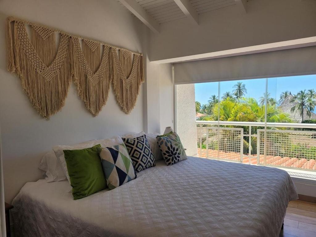 ein Schlafzimmer mit einem Bett und einem großen Fenster in der Unterkunft Terrazas de Guacuco TH in Playa Guacuco