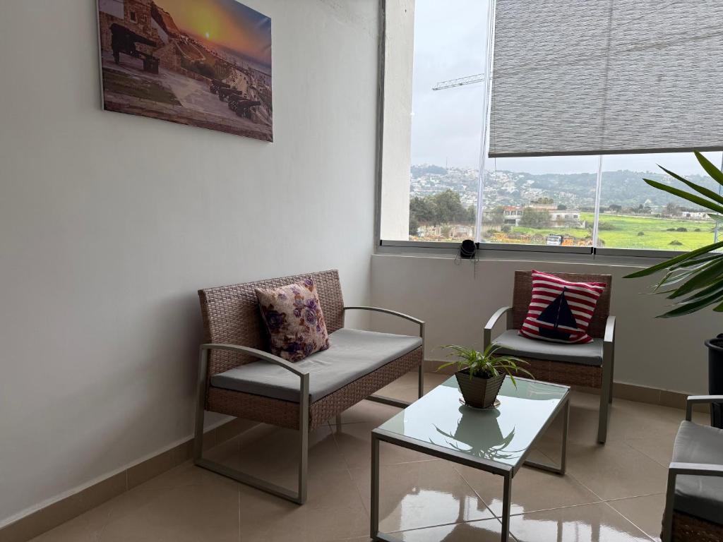 a waiting room with chairs and a table and a window at The Paradise of ACHAKAR in Tangier