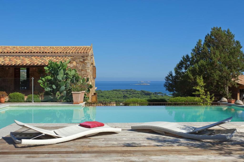 - une piscine avec 2 chaises longues à côté d'une maison dans l'établissement Chambres d'Hôtes Littariccia, à Porto-Vecchio