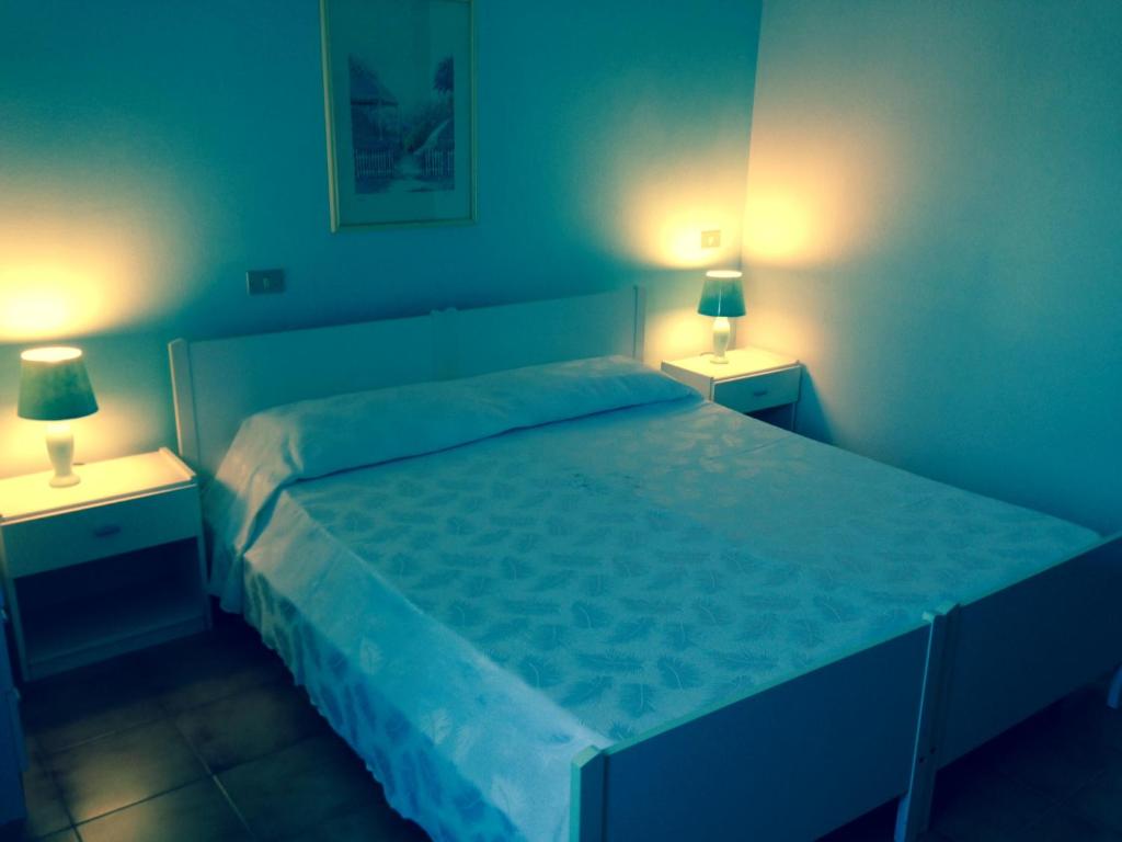 1 dormitorio con 1 cama grande y 2 lámparas. en B&B Andalas, en Olbia