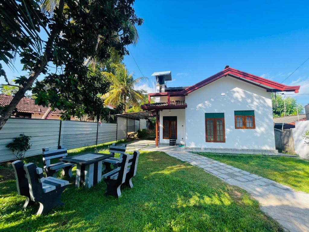 a house with a table and benches in the yard at Villa 10 Weligama in Weligama