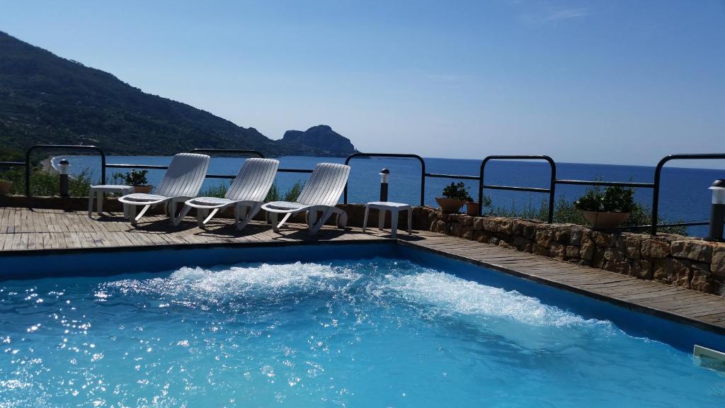a swimming pool with chairs and the ocean in the background at CH Exclusive Apartments in Cefalù