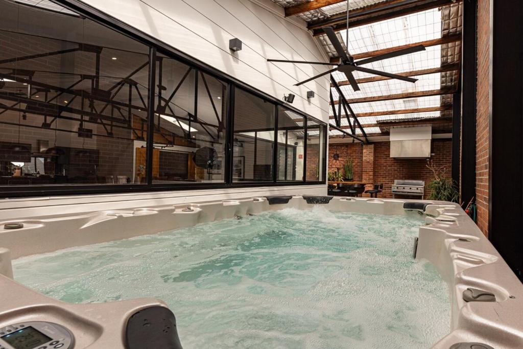 a jacuzzi tub in a room with windows at Newcastle CBD Penthouse, Spa & Entertainment in Wickham