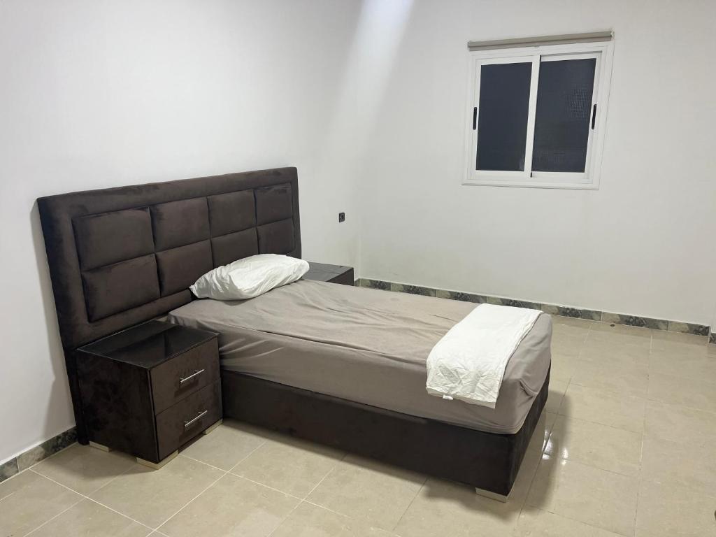 a bedroom with a bed and a nightstand and a window at appartement neuf ideal in Monte ʼArrouit