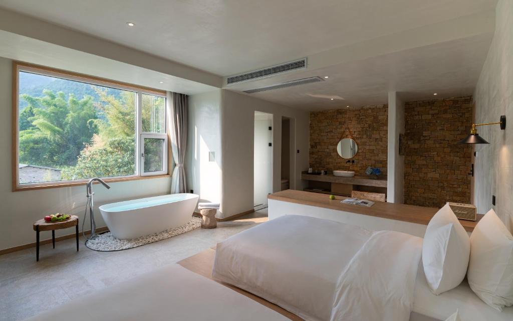 a bedroom with a large bed and a bath tub at Yangshuo One Thousand and One Courtyard Views B&B in Yangshuo