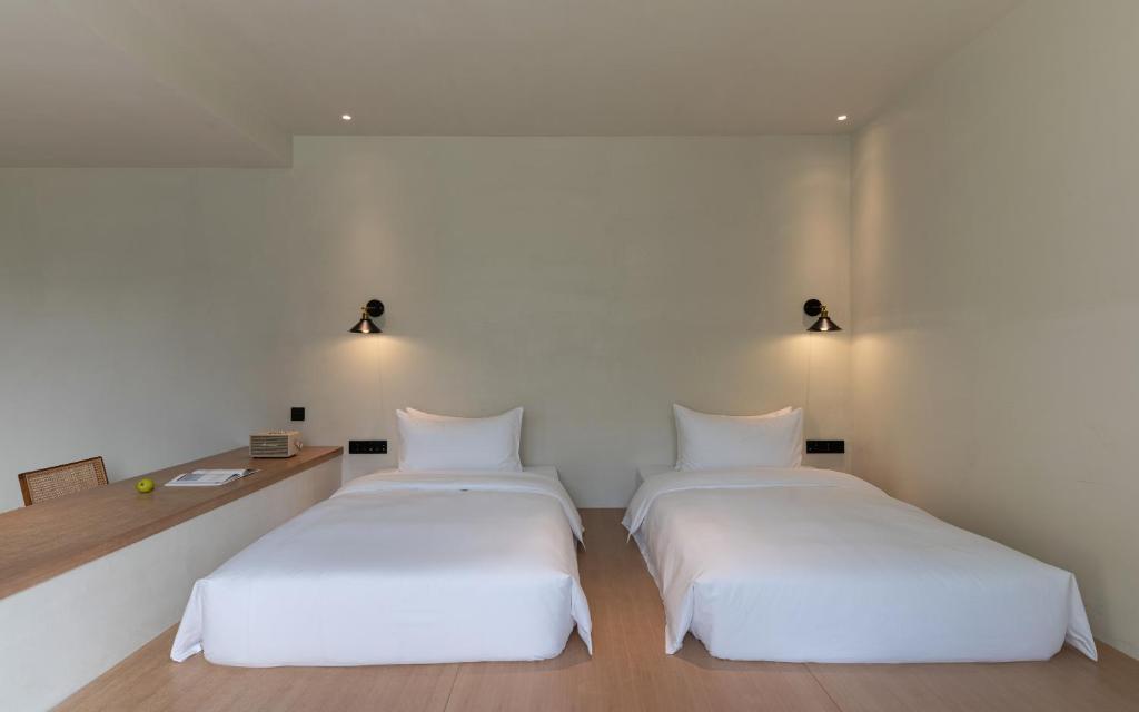 two beds in a room with white walls at Yangshuo One Thousand and One Courtyard Views B&B in Yangshuo