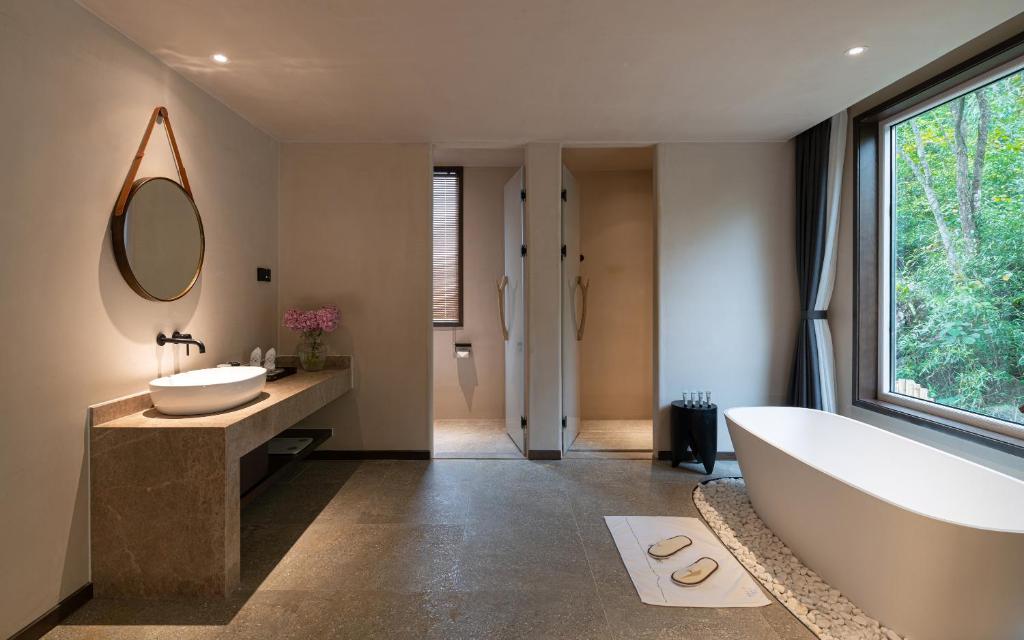 a bathroom with a tub and a sink and a mirror at Yangshuo One Thousand and One Courtyard Views B&B in Yangshuo